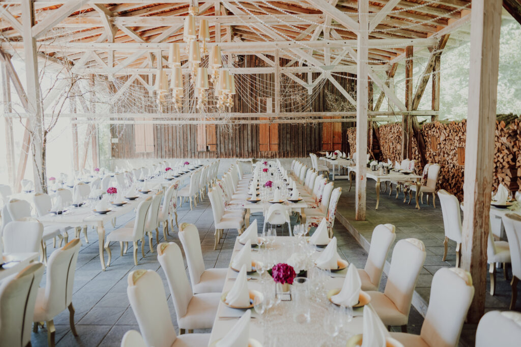 Festlich eingedeckte Hochzeitstafeln mit Blumen und Kerzen in der rustikalen Scheune von Magical Homes in Heroldstatt