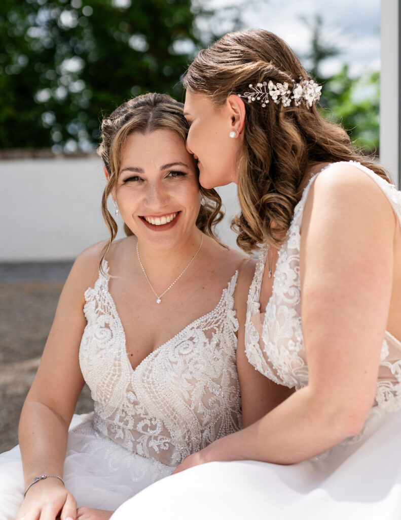 Gleichgeschlechtliches Brautpaar Simone und Laura in weißen Hochzeitskleidern bei ihrer deutsch-russischen Hochzeit im Auwald Sportzentrum