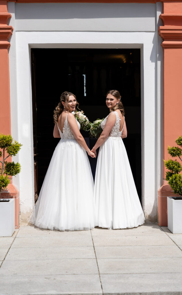 Zwei Frauen in weißen Brautkleidern bei ihrer gleichgeschlechtlichen Hochzeit im Auwald Sportzentrum Gundremmingen
